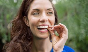 woman placing Invisalign in mouth